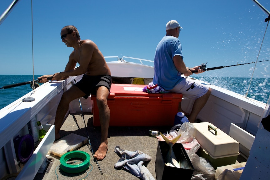 Two men on a boat fishing.