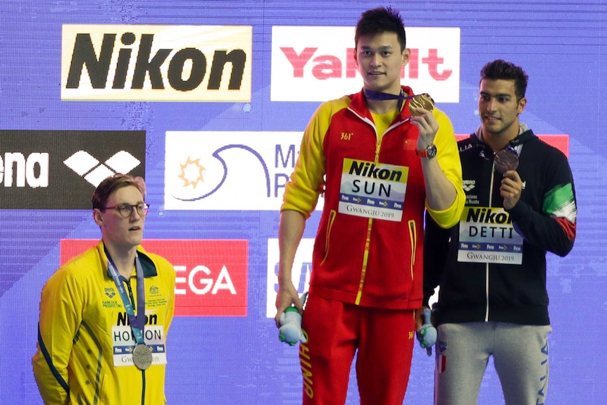 Australia's Mack Horton stands off the podium as Chinese swimmer Sun Yang and Italy's Gabriele Detti hold their medals.