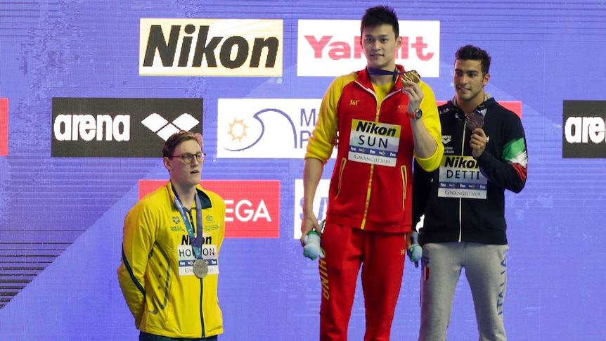 Australia's Mack Horton stands off the podium as Chinese swimmer Sun Yang and Italy's Gabriele Detti hold their medals.