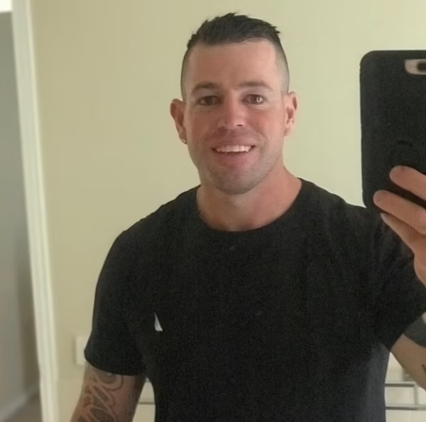 Man in black shirt holds up phone for selfie