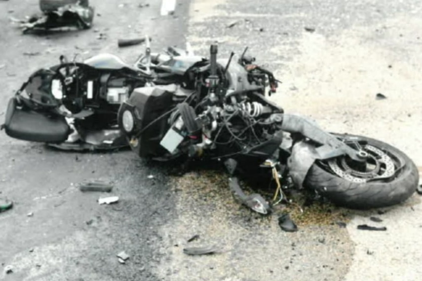 A smashed motorcycle lays in pieces on the road