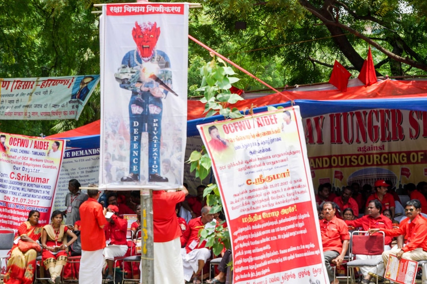 People sit in the background behind various posters protesting privatisation