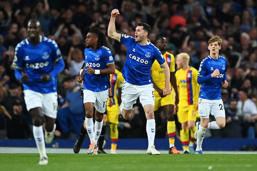 Soccer players wearing blue and white celebrate after scoring an important goal