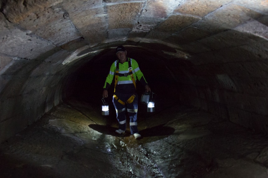 Sydney Water worker carries lamps inside the Tank Stream