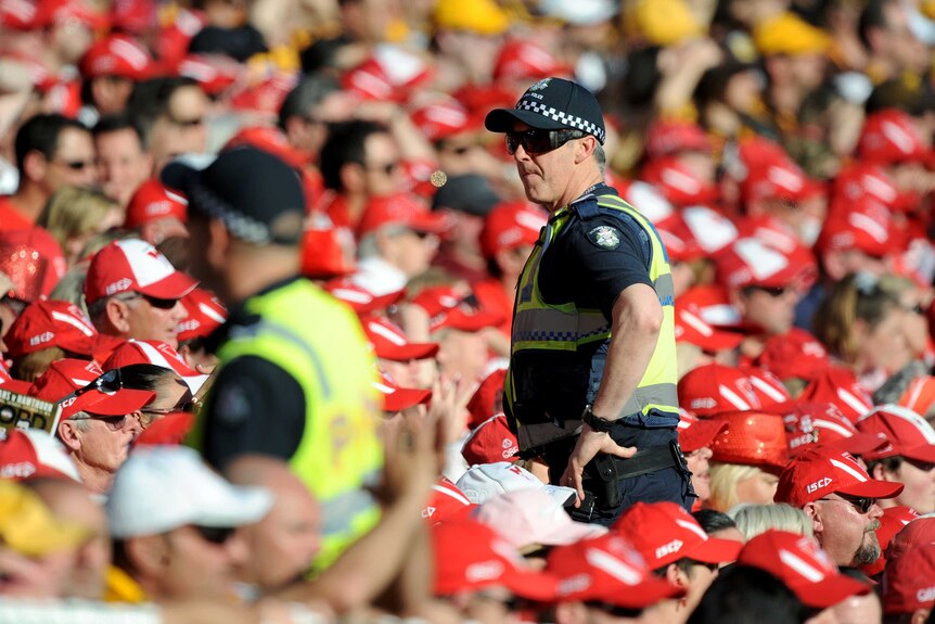 Two police officers walk through the crowd at the 2014 AFL grand final at the MCG.