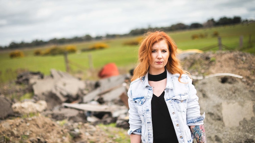 A woman with red hair stands in a field