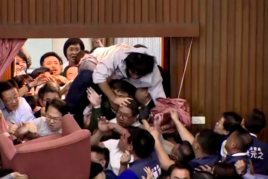 a man climbs over other politicians