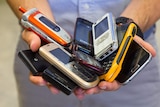 Close-up of man's hands holding a pile of mobile phones.