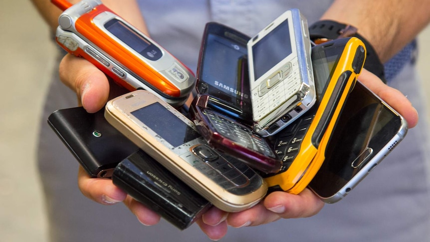 Close-up of man's hands holding a pile of mobile phones.