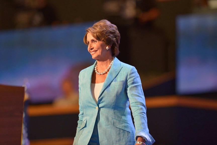 Nancy Pelosi smiles at the audience as she walks on stage