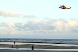 A helicopter hovers above a beach