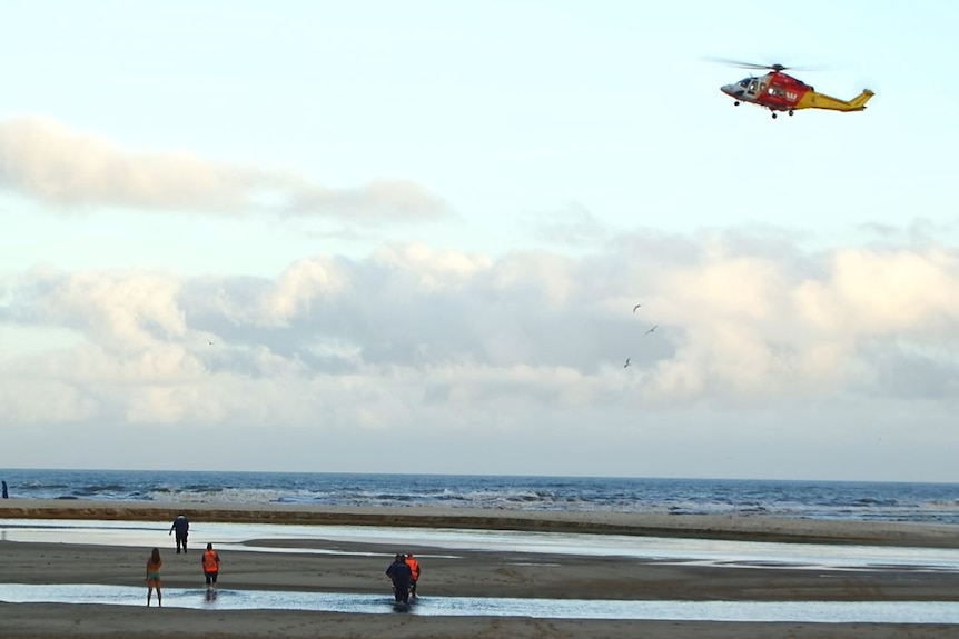 A helicopter hovers above a beach