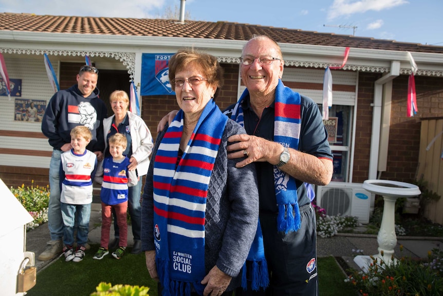 Lou Thompson stands with three generations of his family outside their home, dressed in bulldogs merch.