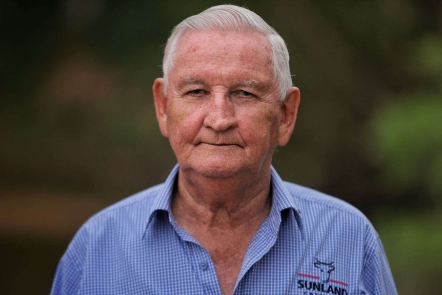 A man with grey hair looks into the camera with a serious expression on his face.