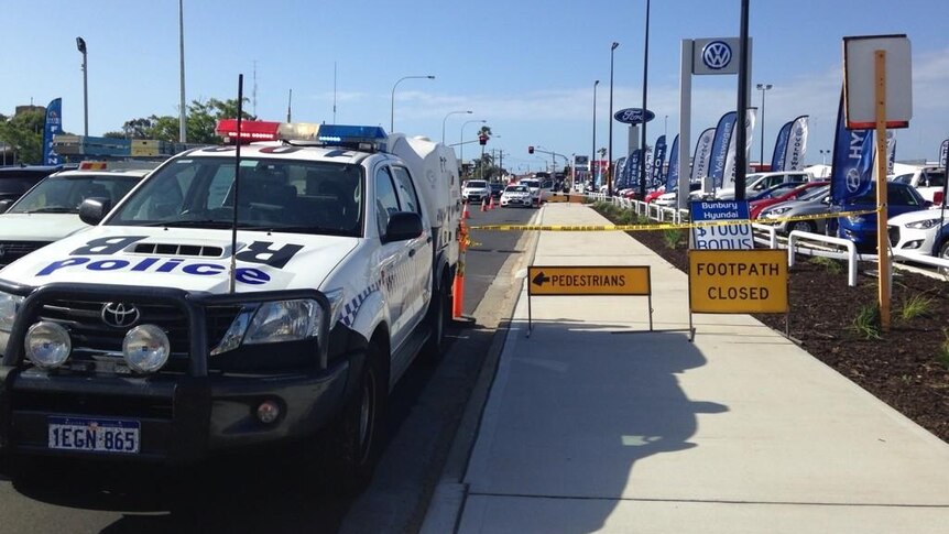 Several police cars are lined up next to a caryard where a man was found severely injured in Spencer Street, Bunbury