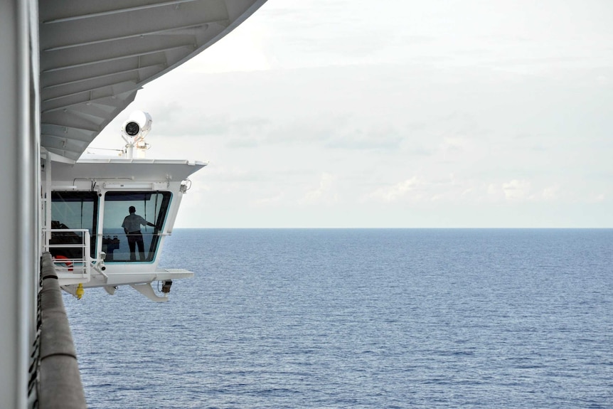 An officer on a cruise ship watches from the Bridge.