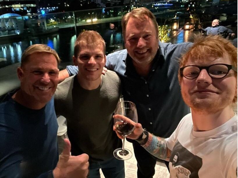 Shane Warne, Jackson Warne, another man and Ed Sheeran pose for a selfie in Melbourne at night.