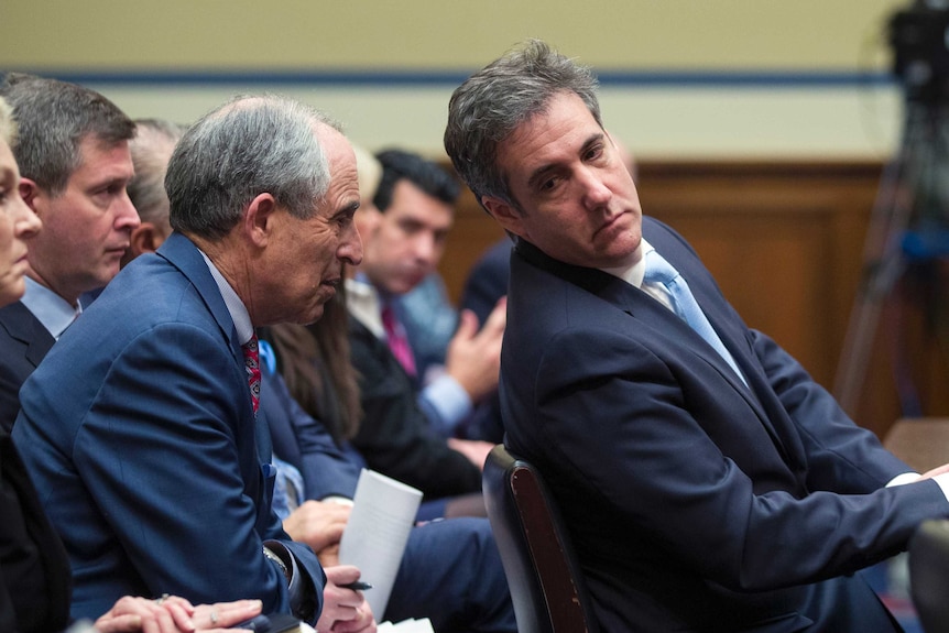 Michael Cohen talks to his lawyer during a House heading