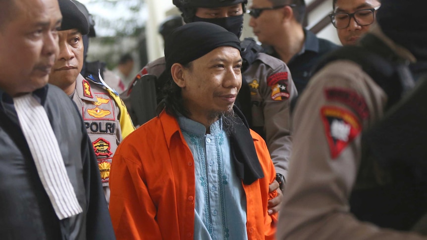 Terdakwa teroris Aman Abdurrahman masuk ke ruang pengadilan di Jakarta hari Jumat (22/6/2018)