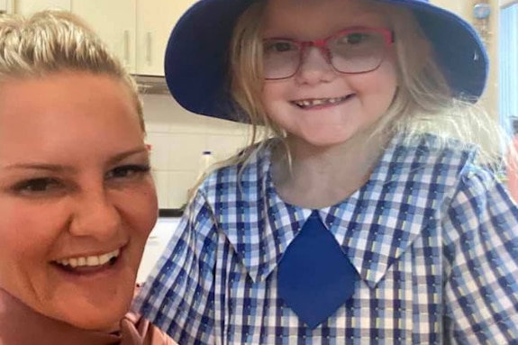 Harper in a school uniform next to her mother. 
