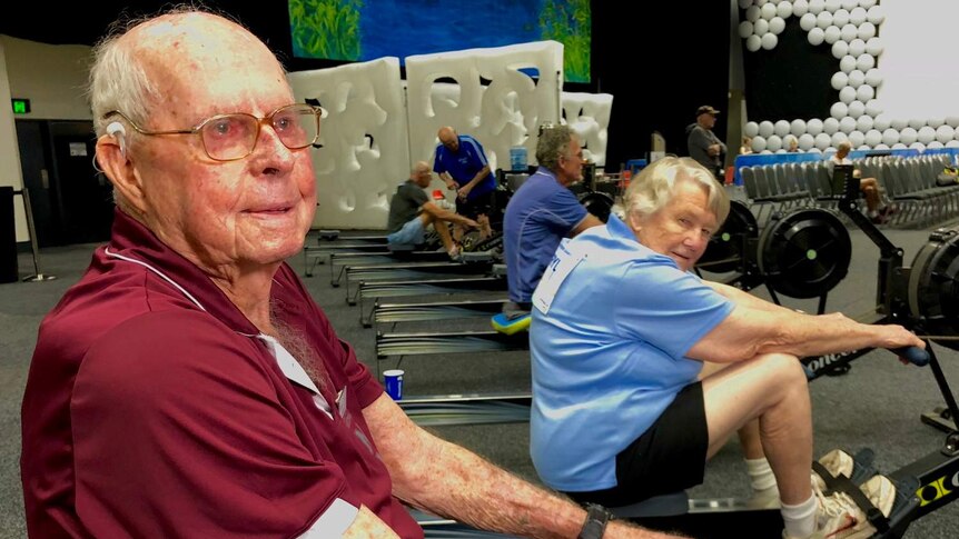 Elderly man and his wife practicing on indoor rowing machines.