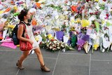 Woman walks past flowers at Martin Place
