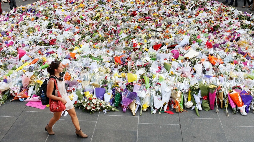 Woman walks past flowers at Martin Place