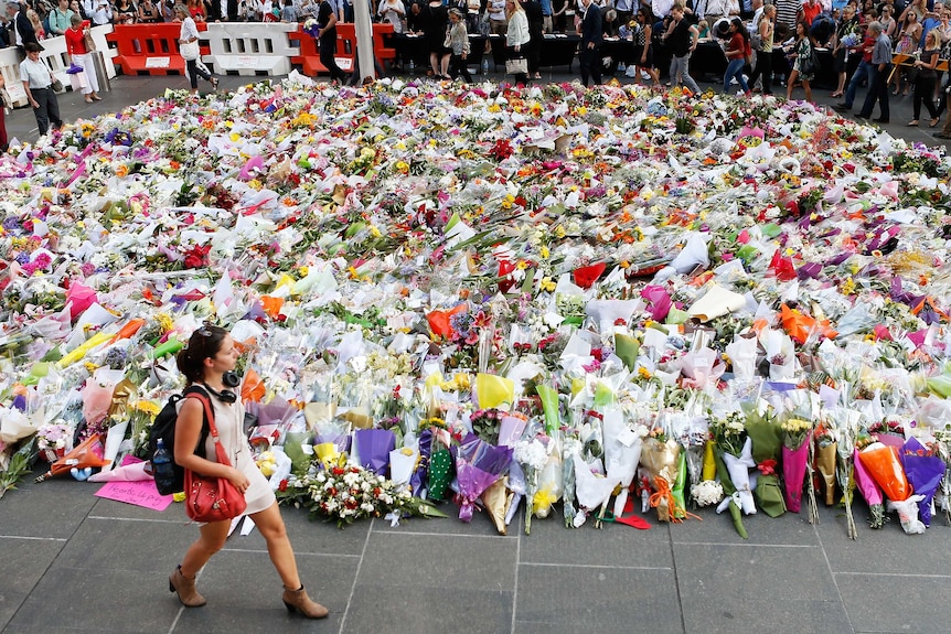 Woman walks past flowers at Martin Place