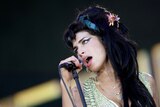 A close up of Amy who is singing into the microphone and tilting her head to the left. 
