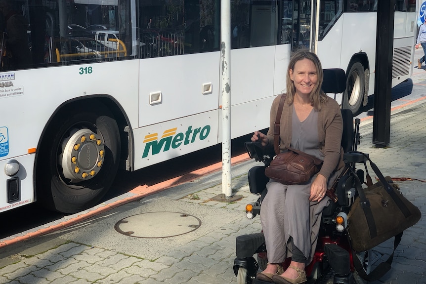 Woman in motorised chair with bags, bus in background