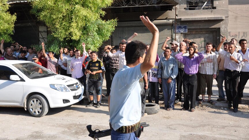 A Syrian rebel fighter salutes Aleppo locals