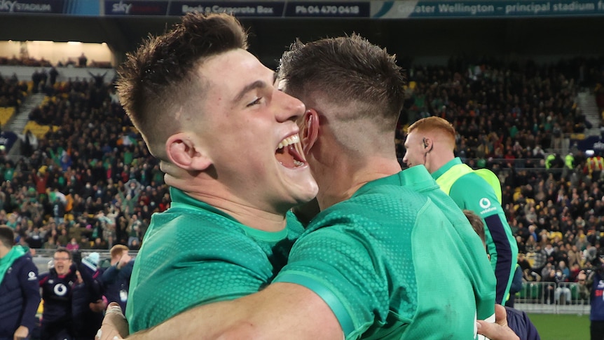Two male Irish Test rugby union players embrace after defeating the All Blacks.