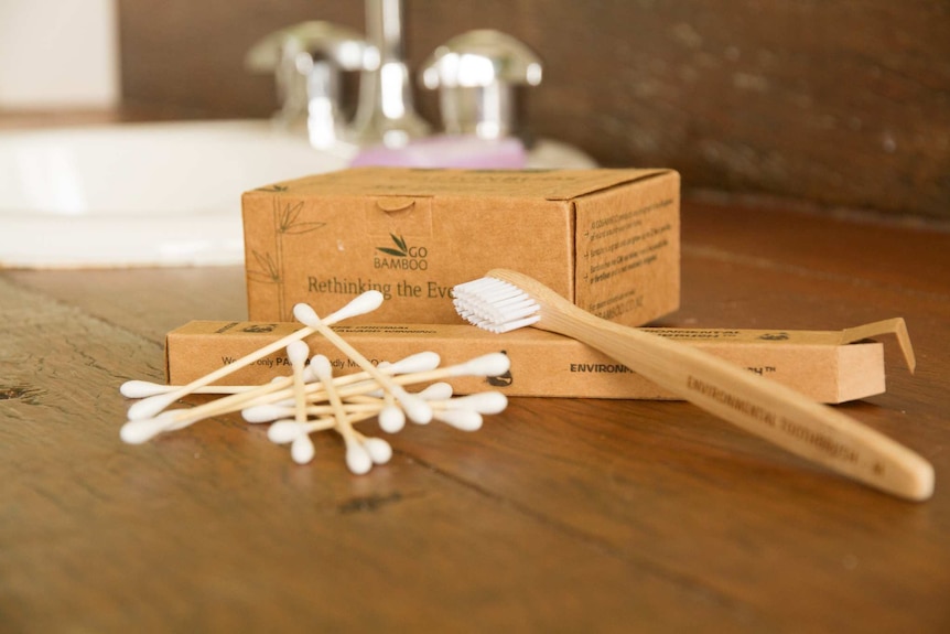 Bamboo toothbrushes and cotton buds on a bathroom benchtop.