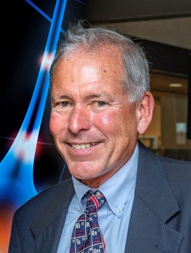 A man in a suit smiles at the camera.