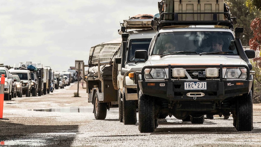 Row of cars and caravans queuing to cross the WA/SA border.