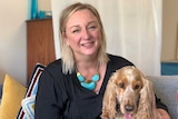 Keilor Lodge resident Jodi Gordon, a woman with blonde hair, smiles at the camera next to her dog.