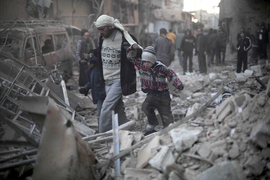 A man and his children walk through the debris of buildings destroyed by an airstrike.