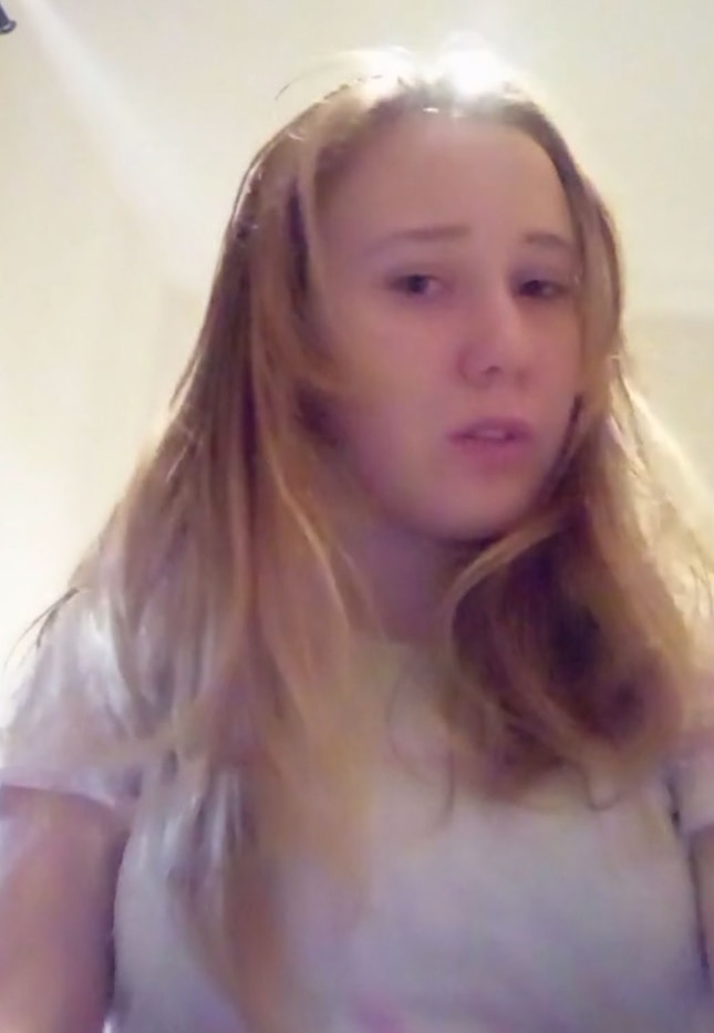 a young blonde teenage girl looks at the camera