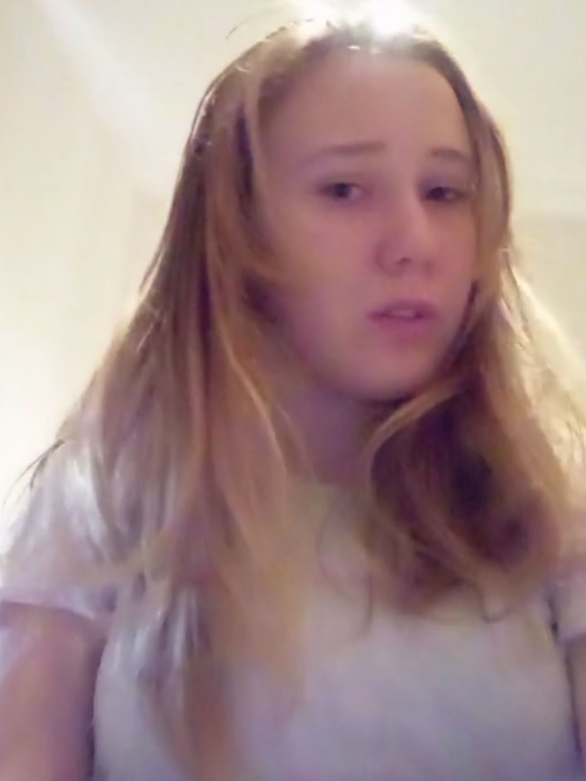 a young blonde teenage girl looks at the camera