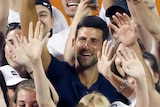 Novak Djokovic can be seen among a large number of young volunteers, waving on court