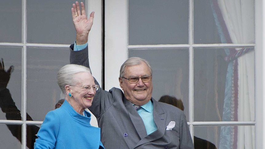Queen Margrethe and Prince Henrik standing on balcony and greeting people