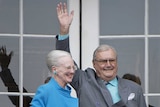 Queen Margrethe and Prince Henrik standing on balcony and greeting people