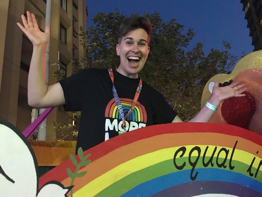 Steff smiles on top of a rainbow at a pride event.