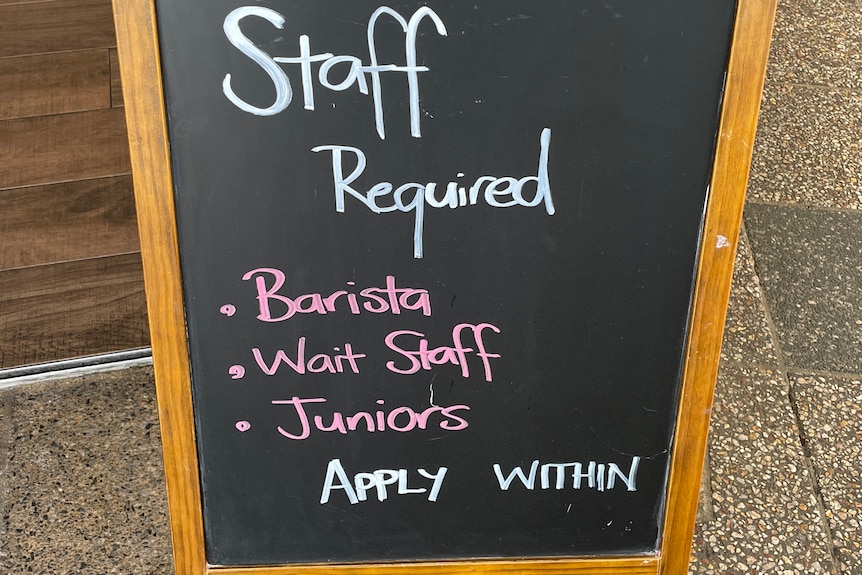 a blackboard outside a cafe advertising for staff 