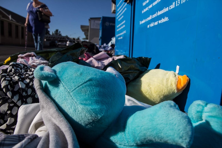 Dumped soft toys and clothing outside a vinnies bin