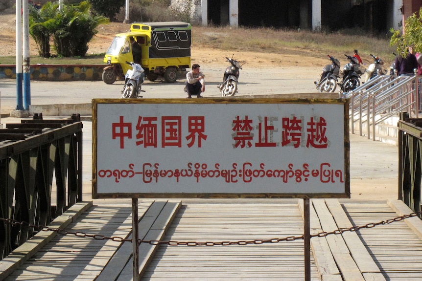 在这张2009年1月12日的文件照片中，在靠近云南省瑞丽市的万宁市边境，连接中国和缅甸的桥梁上有一个标志，用中文和缅甸语警告人们不要越过边境。