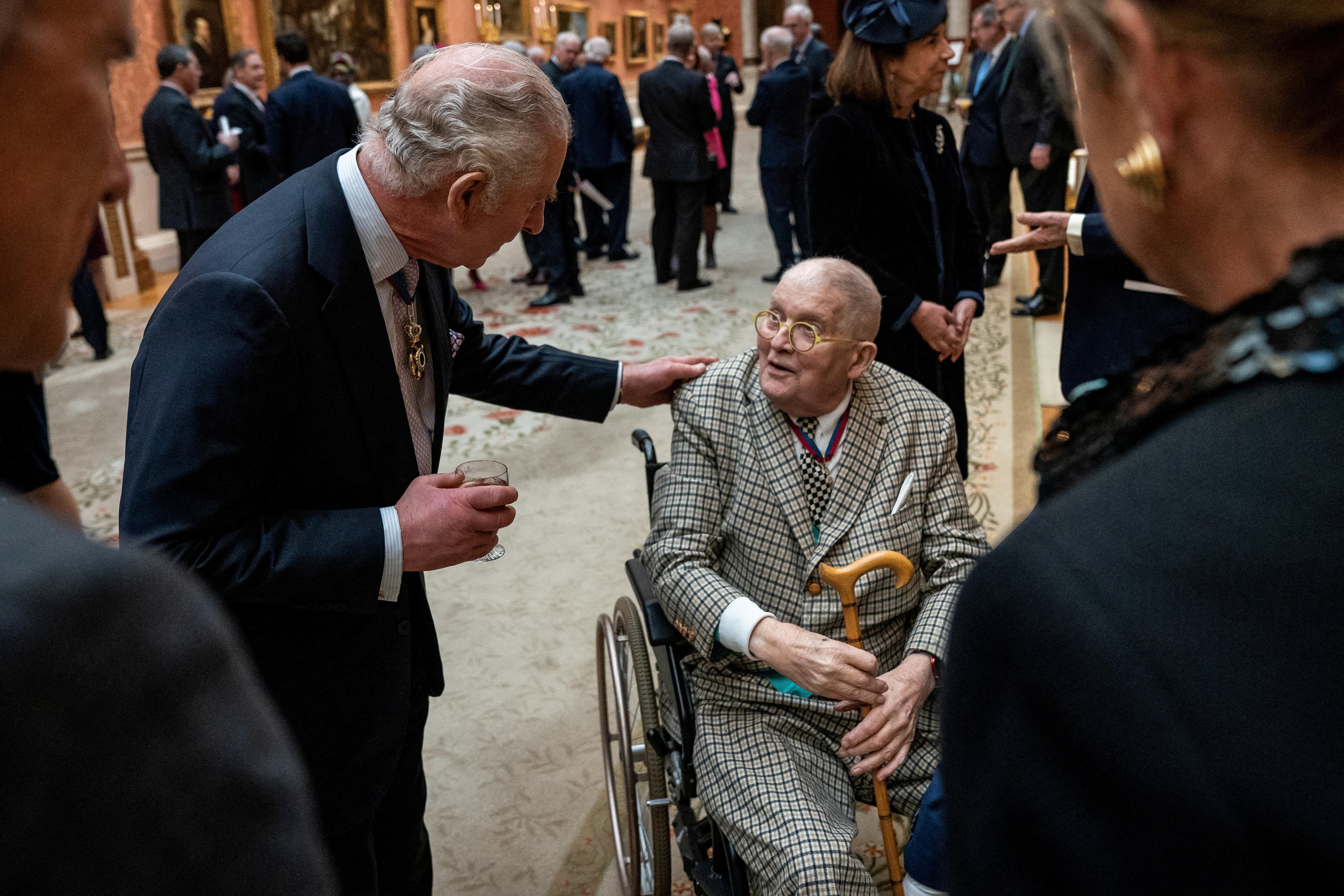 King Charles talks to an old man in a wheelchair