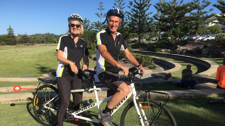 Ruth and her husband are sitting astride their tandem bike.