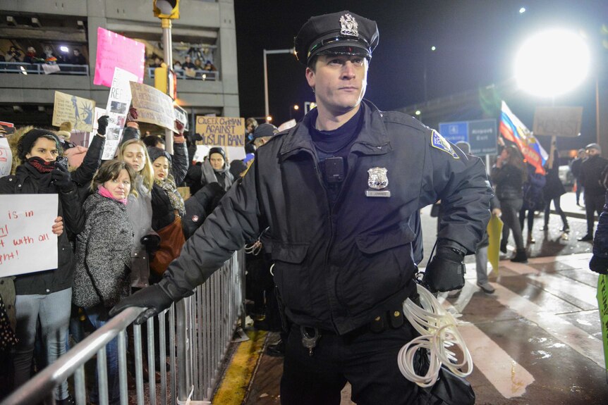 A police officer stands guard as protestors rally