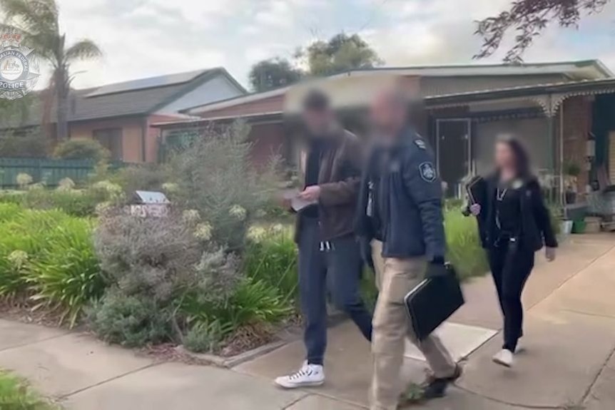 Three people with blurred faces leaving a suburban house.